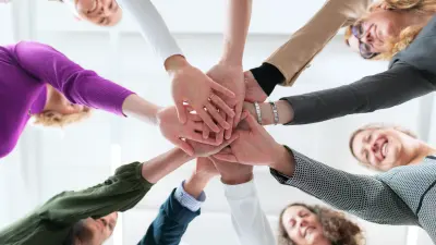 Teammitglieder reichen sich die Hände in einer Geste der Einigkeit und Zusammenarbeit.