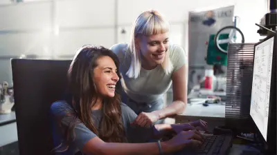 The image shows two women using ASCET on a computer. They are both looking at the screen in an office setting.