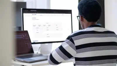 Mann sitzt vor PC-Bildchirm und schaut auf eine Anwendung