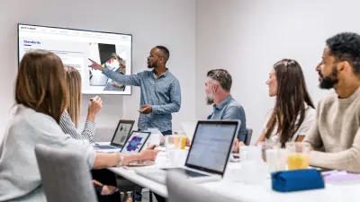 Des personnes sont assises dans la formation AUTOSAR sequrity. Et le formateur montre quelque chose sur l'écran plat.