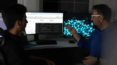 Deux hommes sont assis devant un PC et discutent des contenus