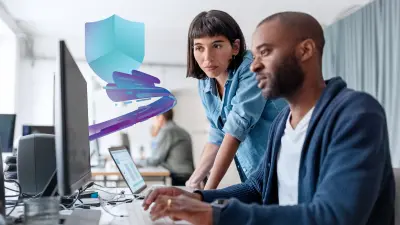 Two cybersecurity professionals collaborate on a computer, analyzing data. A shield icon in the background symbolizes security. This image highlights ETAS Security test consulting services, emphasizing expert testing and consulting to enhance automotive cybersecurity.