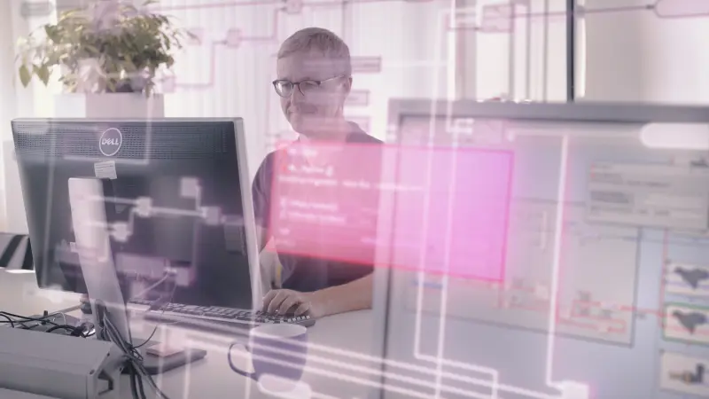 The image shows a man sitting in front of a PC, coding an ECU software application. The picture has an overlay of an image of the EHANDBOOK software.